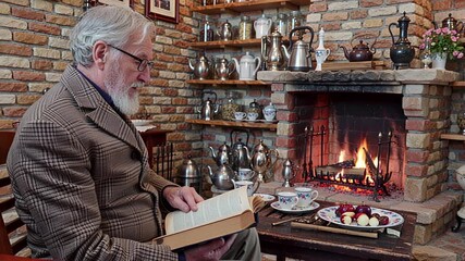 elderly man reading book by cozy fireplace, warm interior scene | retirement, relaxation, leisure, home, storytelling theme - Powered by Adobe