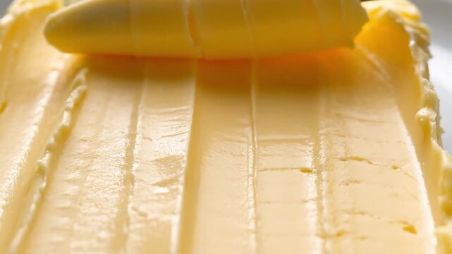 Extreme macro close up of soft yellow creamy butter with textured parallel ridges and grooves from being spread or cut