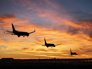 Silhouetted airliners landing at Seville Airport during sunset