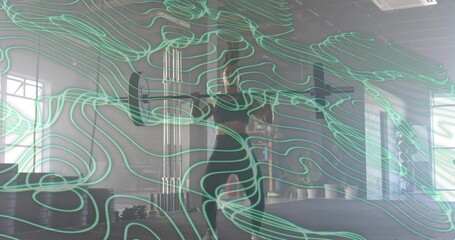 Standing woman in black gear adjusting hair in gym studio with mirror, plates and teal lines