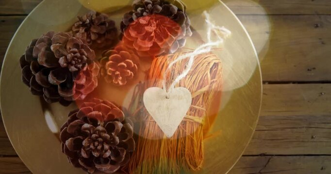 Shifting bokeh lights revealing round dish with pine cones and heart tag, showing rustic decor