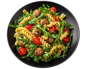 Spiral pasta with meatballs, arugula, and cherry tomatoes on a dark plate