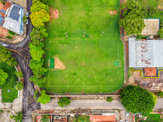 Overhead view of a vibrant green soccer field nestled among buildings and trees, showcasing urban recreation and community space in brazil