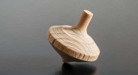 Minimalist wooden spinning top on a reflective surface for creative uses