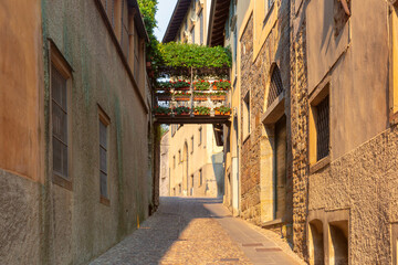 Cobblestone alley with floral bridge and historic buildings in Bergamo, Lombardy, Italy
