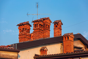 Close-up of traditional brick chimneys with roof tiles in Bergamo, Lombardy, Italy