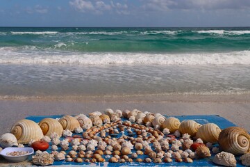 na Tunezyjskiej plaży skromny kramik, stolik handlarza muszlami. w tle błękitne morze. © Pawel Zabczyk
