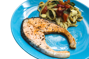A tasty gourmet meal of grilled salmon steak, a delicious dinner dish cooked with fresh vegetables on a plate