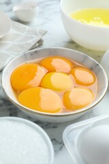 Egg yolks, whites and sugar on white marble table, closeup
