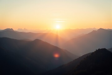 Obraz premium Golden sunbeams illuminate misty mountain peaks at dawn.