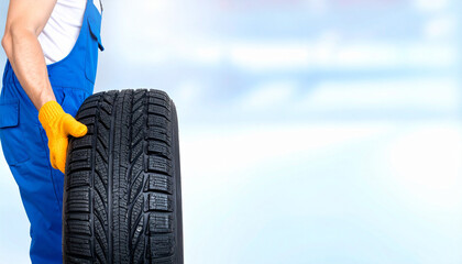 Mechanic holding a car tire, ready for replacement or repair with a clean, bright background