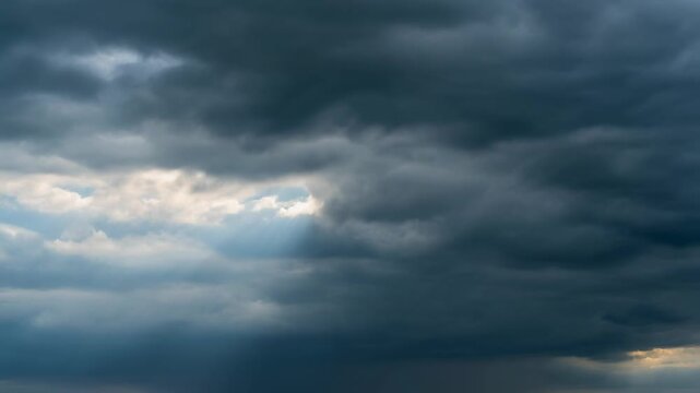 Dark, ominous storm clouds gather in a dramatic sky, with a sliver of brighter light peeking through.