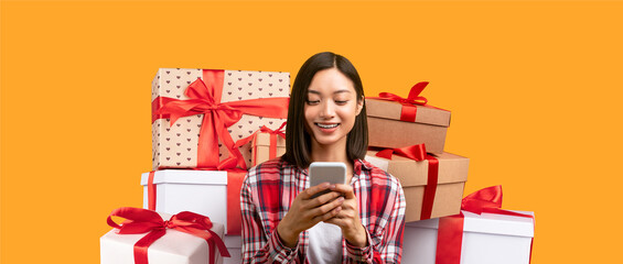 A woman is smiling while using her smartphone, surrounded by colorful wrapped gifts. The scene captures a joyful moment, perfect for the holiday season or special occasion.