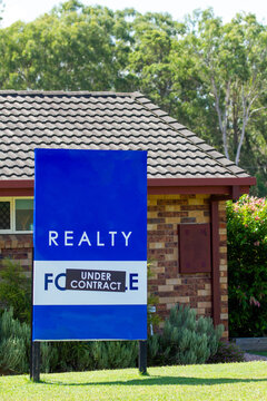 Real estate for sale under contract sign outside brick home in North Brisbane.