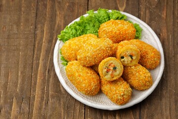 Kroket kentang. Croquettes are lumps of finely mashed potatoes filled with seasoned minced meat and mixed with vegetables such as carrots or green beans. The croquettes are coated with beaten egg and 