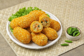 Kroket kentang. Croquettes are lumps of finely mashed potatoes filled with seasoned minced meat and mixed with vegetables such as carrots or green beans. The croquettes are coated with beaten egg and 