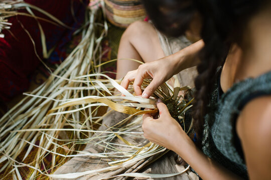 A girl with braided long hair working on a long fibrous material for weaving.