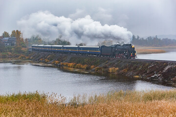 Steam retro train moves along the lake.