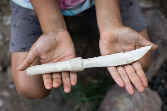 Hands holding hand carved wooden knife