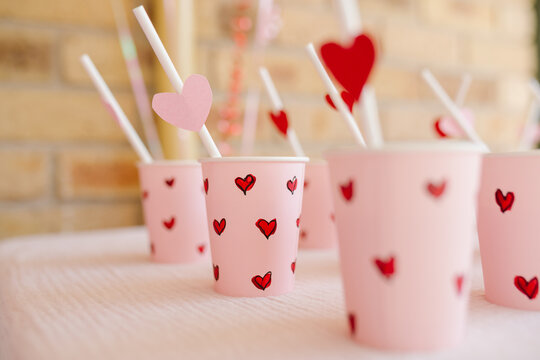 Set of paper cups with small red heart designs and straws.