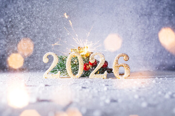 Golden 2026 numbers with a sparkling firework and snowy pine branches on a winter background. Festive Christmas and New Year celebration concept with bright lights and snowflakes for greeting cards.