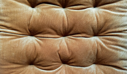 A soft brown tufted fabric texture with gentle folds and velvety sheen, giving a warm, elegant look ideal for upholstery, background, or interior design visuals.