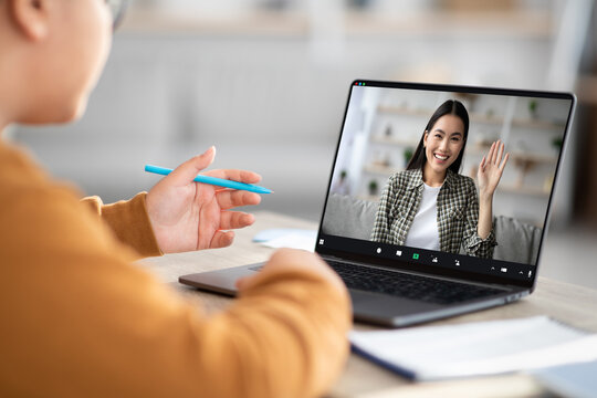 A chubby child is happily having an online class with a cheerful female tutor. They are using a modern laptop in a cozy home setting, focused on learning together.