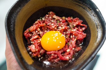 A bowl of raw beef and raw egg mixture before eating, highlighting the richness and texture of the ingredients.