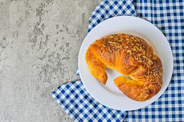 Top view of one cheese croissant on white plate. close up. napkin. cement background. High angle, above, flat lay. copy space, empty, free, negative, text, design.