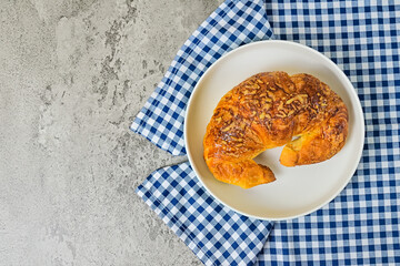 Top view of one cheese croissant on white plate. close up. napkin. cement background. High angle, above, flat lay. copy space, empty, free, negative, text, design.