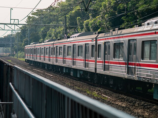 Commuter train traveling along railway tracks surrounded by greenery, representing urban transportation, mobility, and sustainable travel infrastructure.