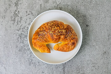 Top view of one cheese croissant on white plate. close up. grey or gray cement on the background. High angle, above, flat lay.