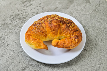Close up view of one cheese croissant on white plate. close up. grey or gray cement on the background. 