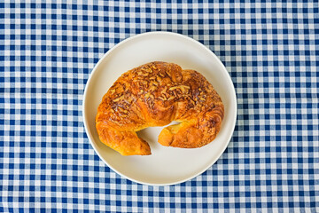Top view of one cheese croissant on white plate. close up. isolated on the napkin background. High angle, above, flat lay.