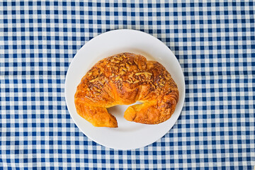 Top view of one cheese croissant on white plate. close up. isolated on the napkin background. High angle, above, flat lay.