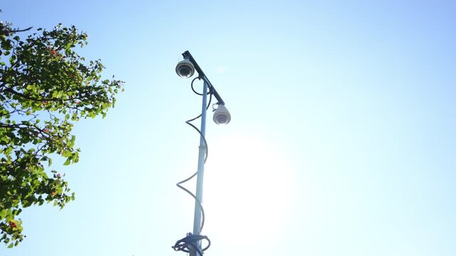 Close up of mobile police surveillance tower with multiple security cameras raised on a telescoping mast in a suburban neighborhood with blue sky. public safety and security