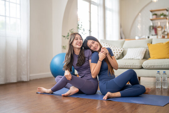 Two woman partner resting after yoga stretching fitness with smiles at home, flexibility exercise together, healthy lifestyle with friend, mindfulness and wellness, fitness blogger at home workout