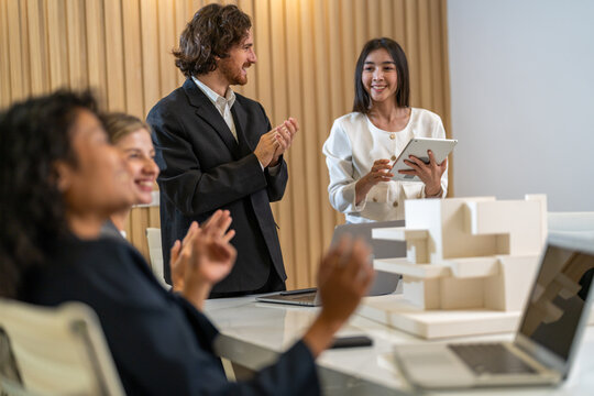 Architects engineers collaborating on building design project in modern office, diverse team of professionals female muslim architect and male engineers discussing architectural model of structure