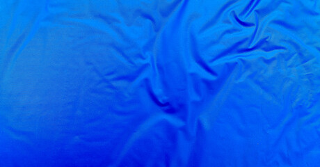Smooth blue waterproof fabric with light wrinkles and soft reflections, ideal for background, design mockups, or outdoor gear material texture close-up.