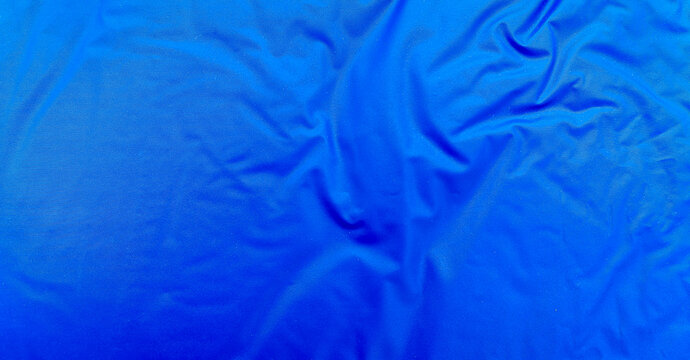 Smooth blue waterproof fabric with light wrinkles and soft reflections, ideal for background, design mockups, or outdoor gear material texture close-up.