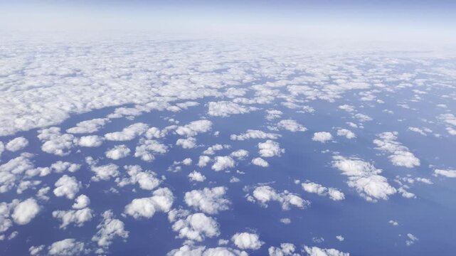 View from airplane flying above clouds &ndash; peaceful sky and soft sunlight over white cloudscape

