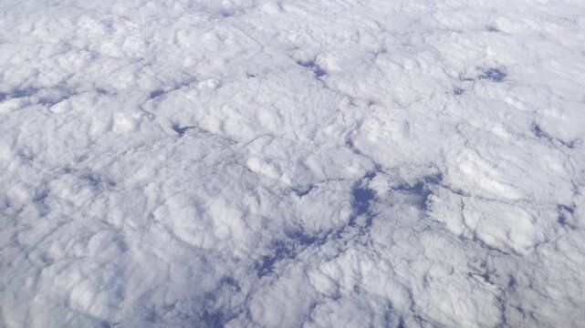 View from airplane flying above clouds &ndash; peaceful sky and soft sunlight over white cloudscape
