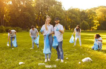 Happy volunteer group, friends working happily in sunny green park, diverse team smiling, holding bags and wearing gloves, feeling accomplished volunteering and cleaning environment, thumbs up showing