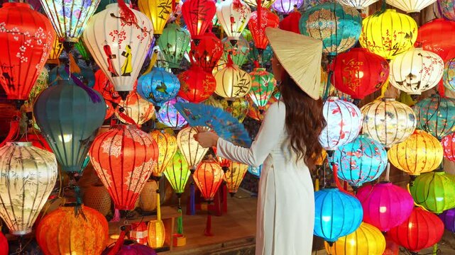 4K slow motion footage of woman wearing traditional Vietnamese cultural dress with colorful lanterns in Hoi An ancient town, Vietnam.