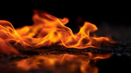 Fototapeta premium Bright orange flames flicker and dance over a dark surface, creating a vivid reflection that emphasizes the dynamic movement of fire against a black background
