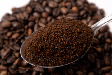 Detail of coffee on a metal spoon over coffee beans