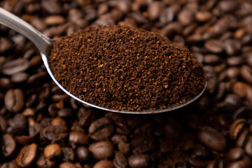 Detail of coffee on a metal spoon over coffee beans