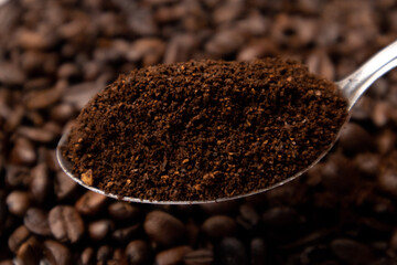 Detail of coffee on a metal spoon over coffee beans