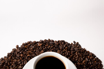 Cup with hot coffee and coffee beans below on a white background