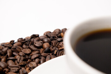 Cup with hot coffee and coffee beans below on a white background